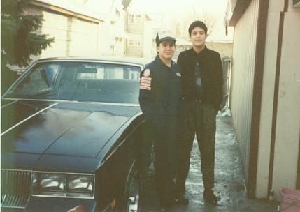 Young Nefty standing proudly next to his classic black Cutlass Supreme years ago